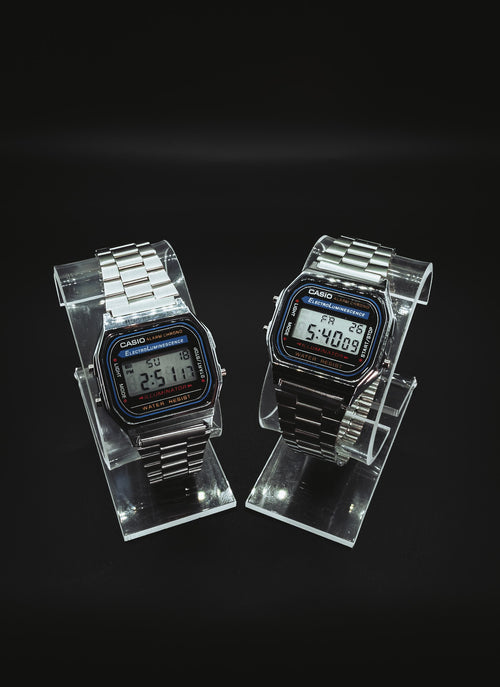 Two Casio A168 digital watches on clear stands
